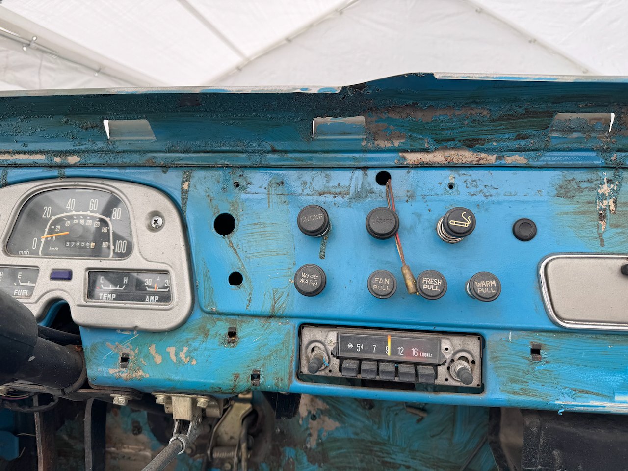 The original FJ40 dashboard: speedometer, pull knobs for choke and heat, and an AM radio