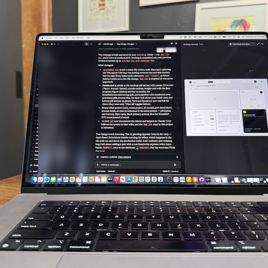 MacBook on a workbench with Claude Code open, describing changes to the BuildLog app